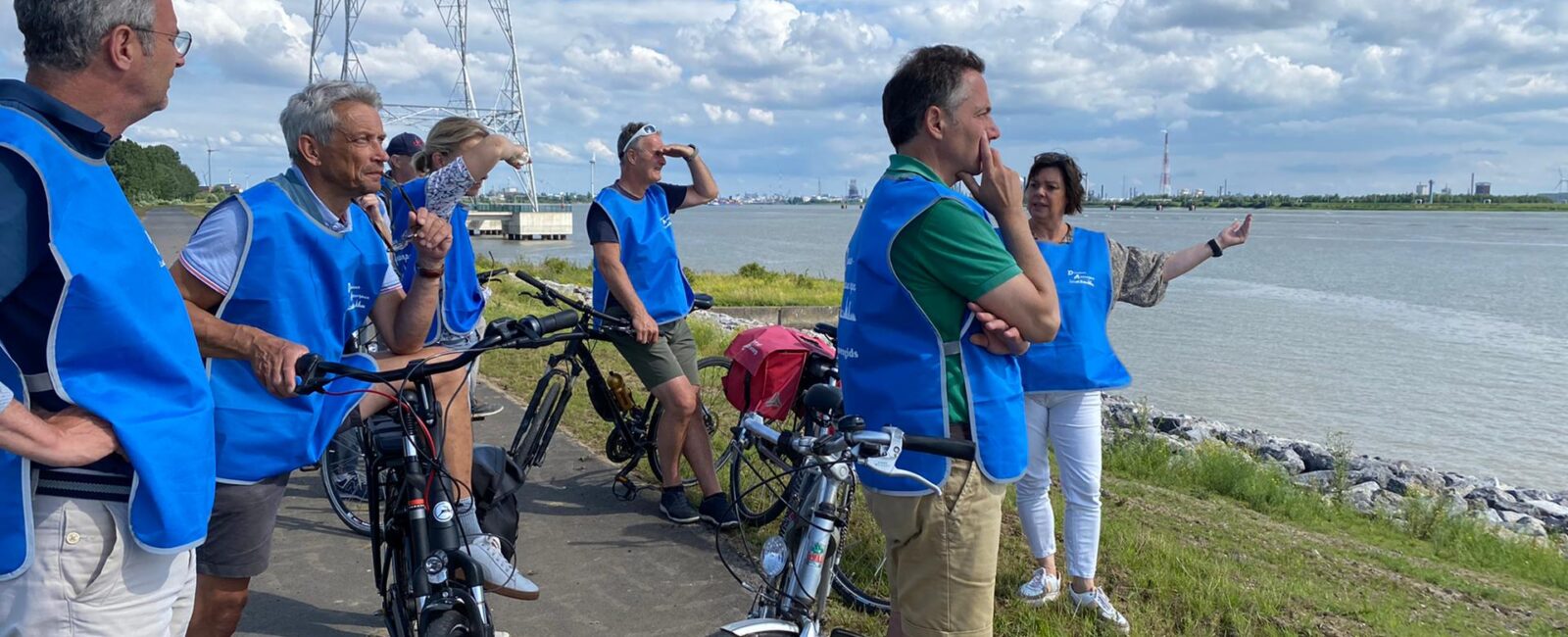 Toeristen met blauwe fluohestjes staan naast hun fietsen