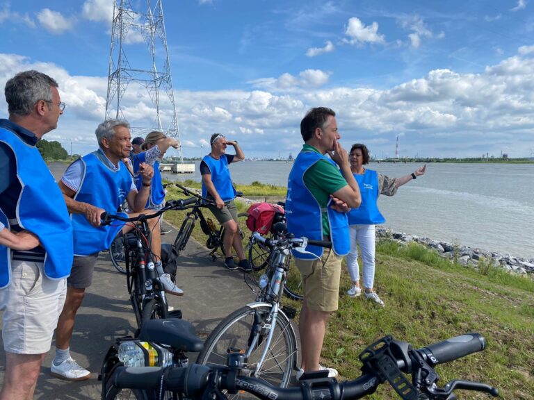 Toeristen met blauwe fluohestjes staan naast hun fietsen