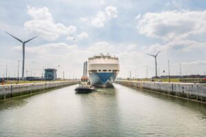Zicht op de Kieldrechtsluis en een autoschip dat getrokken wordt door een sleepboot.
