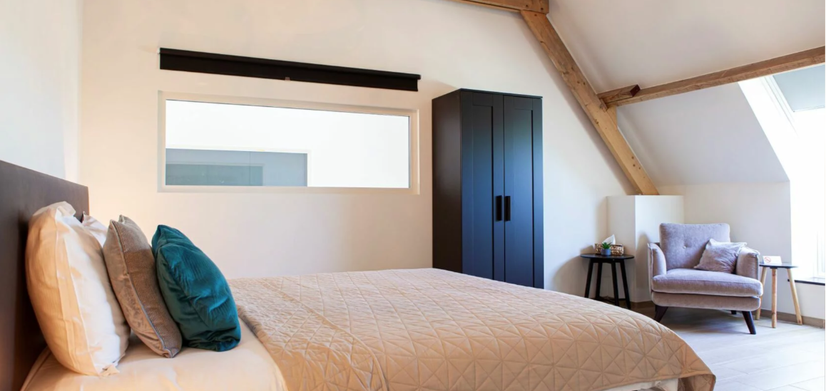 Slaapkamer met zwarte kast, tweepersoonsbed en een sofa