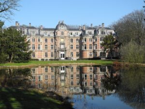 Een foto van kasteel Ravenhof met reflectie van het kasteel in het water.