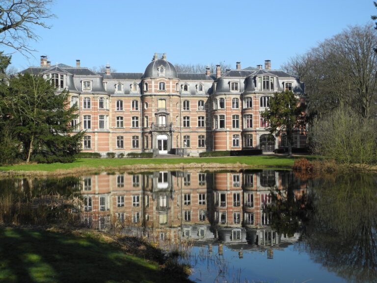 Een foto van kasteel Ravenhof met reflectie van het kasteel in het water.