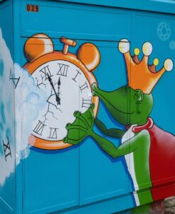elektriciteitskast die beschilderd is met een klok die gekost wordt door een groene kikkerprins, Copyright Hanne Donceel