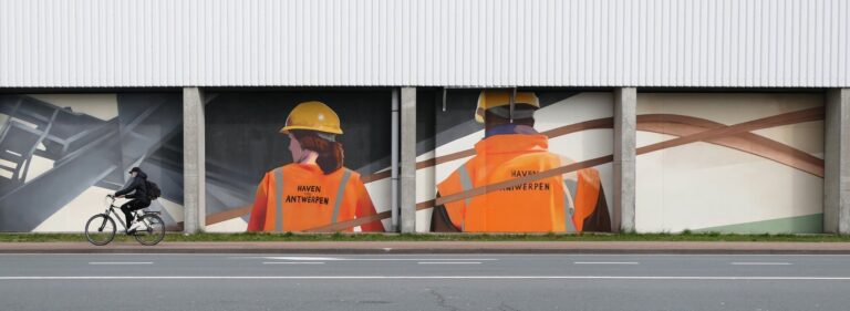 afbeelding van twee havenarbeiders die in rugaanzicht op een muur geschilderd staan, terwijl er een fietser voorbijrijdt