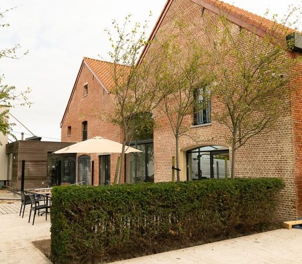 Het gebouw van het hotel met terras en een parasol.
