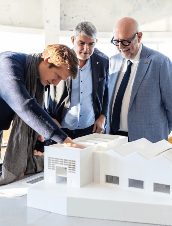 Drie personen kijken naar een witte maquette