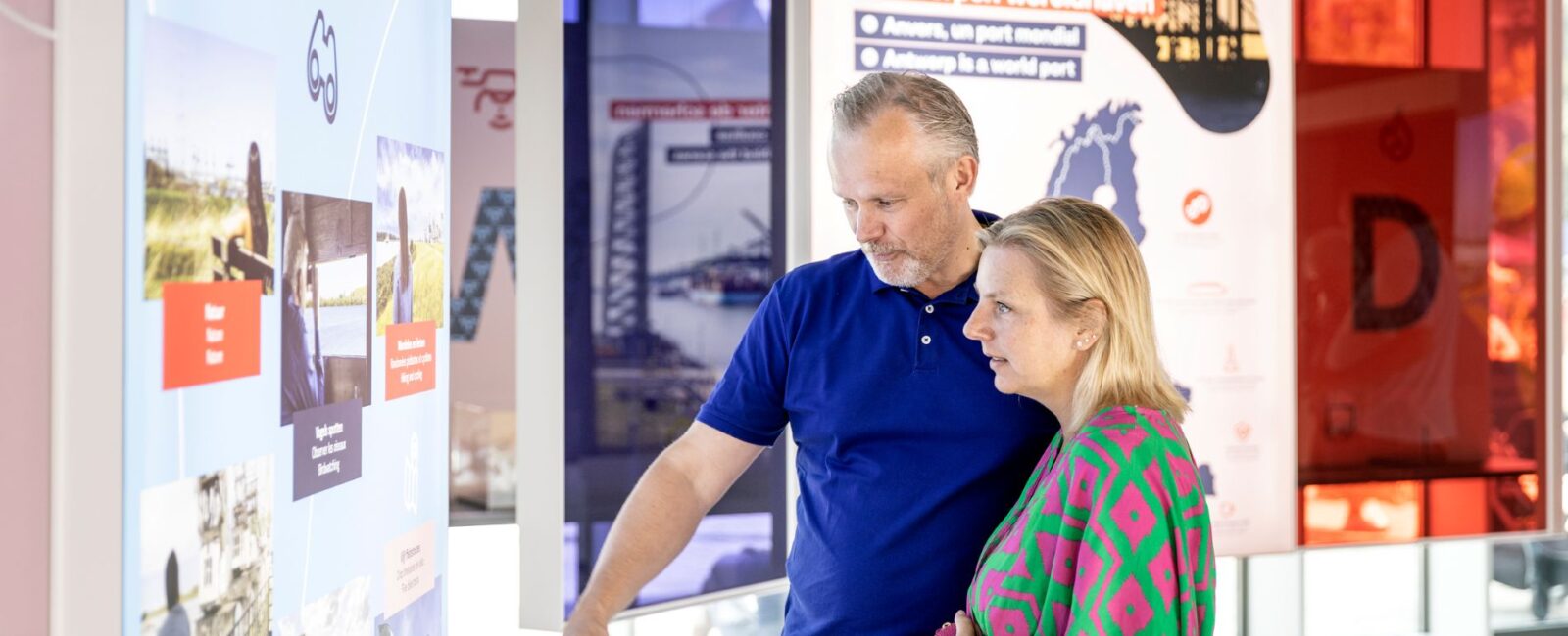 Een man en vrouw die naar een informatiebord kijken in het belevingscentrum Havenwerld.