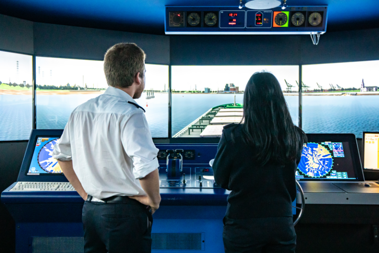 rugaanzicht van man en vrouw die in een cockpit staan en kijken naar diverse schermen, copyright Port of Antwerp-Bruges