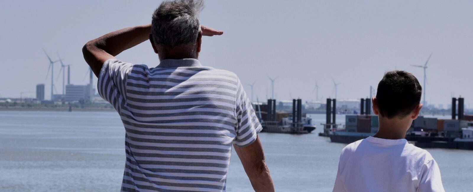 Man en jongen die over de haven uitkijken