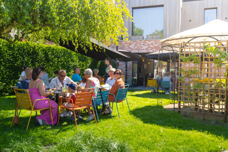 groep mensen zittend aan tafel in een groene tuin